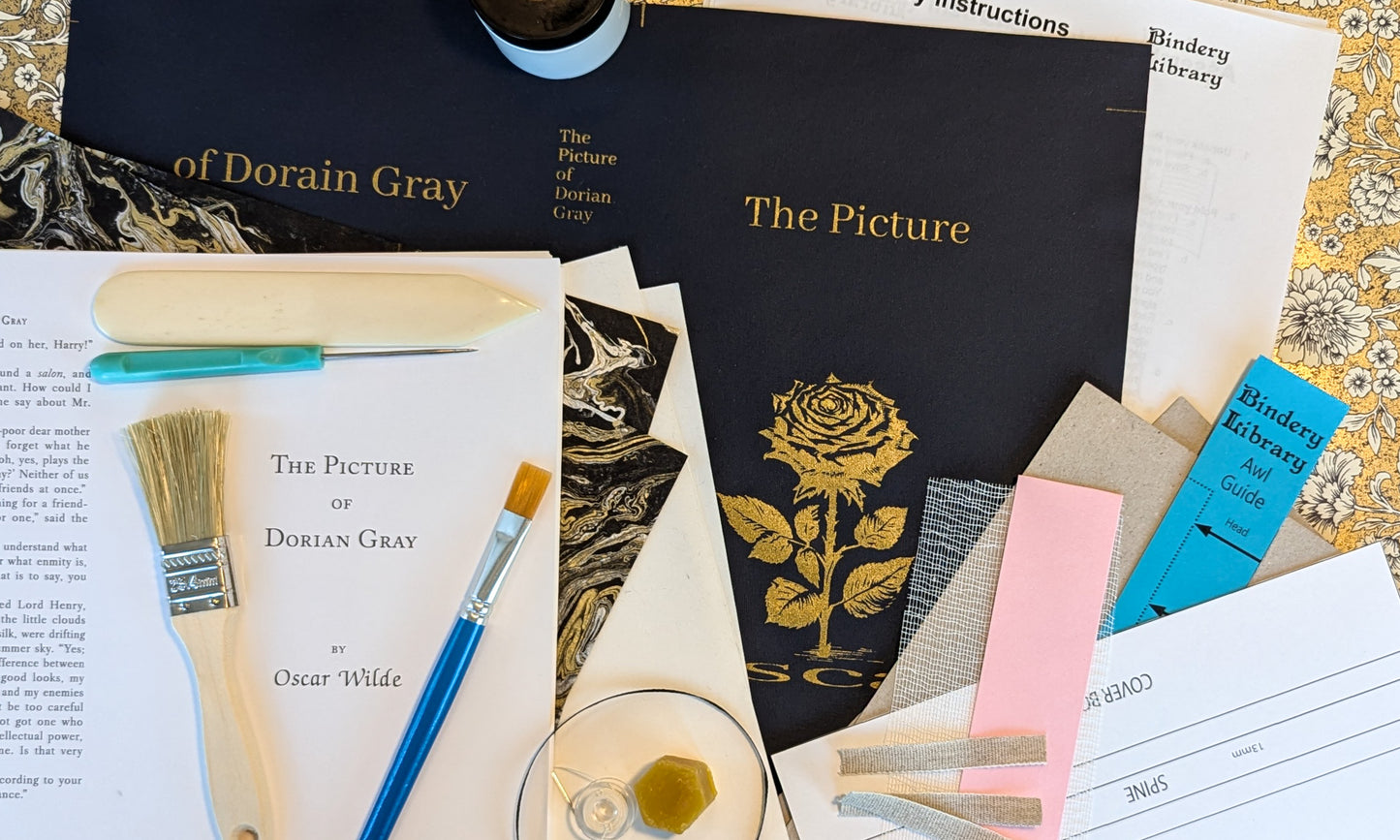 Book titled 'The Picture of Dorian Gray' with art supplies and decorative items on a table.